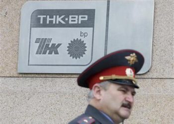 A police officer walks past a plaque of the oil firm TNK-BP at its headquarters in Moscow