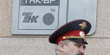 A police officer walks past a plaque of the oil firm TNK-BP at its headquarters in Moscow