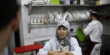 A hearing impaired employee uses sign language to communicate with a co-worker in the kitchen of a restaurant in Gaza