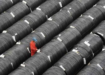 A worker checks on coils of steel at a factory in Dalian