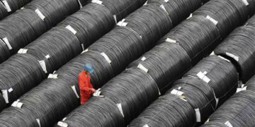 A worker checks on coils of steel at a factory in Dalian