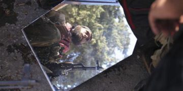 A member of the Free Syrian Army is reflected in a mirror in a house they use as a base in Haram town, Idlib Governorate