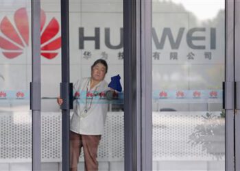 File photo shows a cleaner wiping the glass door of a Huawei office in Wuhan