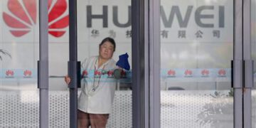 File photo shows a cleaner wiping the glass door of a Huawei office in Wuhan