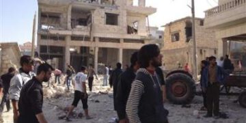 Residents walk on rubble near buildings which are damaged after a Syrian Air Force fighter jet loyal to Syria's President Bashar al-Assad fired missiles at Binsh