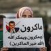 An Arab-Israeli, Muslim demonstrator, holding a child and clad in a mask due to the COVID-19 pandemic, holds up a sign during a rally protesting against French President Emmanuel Macron's anti-Islam remarks, in the Arab town of Umm-Al Fahm, Haifa district, northern Israel, Oct. 25, 2020. (AFP Photo)