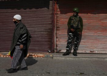 A resident walks past an Indian army soldier standing guard next to closed shops during a one-day strike called by the All Parties Hurriyat Conference (APHC) against the Indian government's decision to open Kashmir land for all Indians, in Srinagar on Oct. 31, 2020. (AFP Photo)