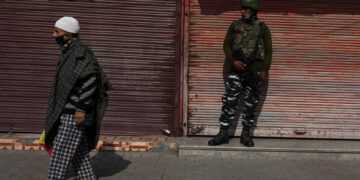 A resident walks past an Indian army soldier standing guard next to closed shops during a one-day strike called by the All Parties Hurriyat Conference (APHC) against the Indian government's decision to open Kashmir land for all Indians, in Srinagar on Oct. 31, 2020. (AFP Photo)
